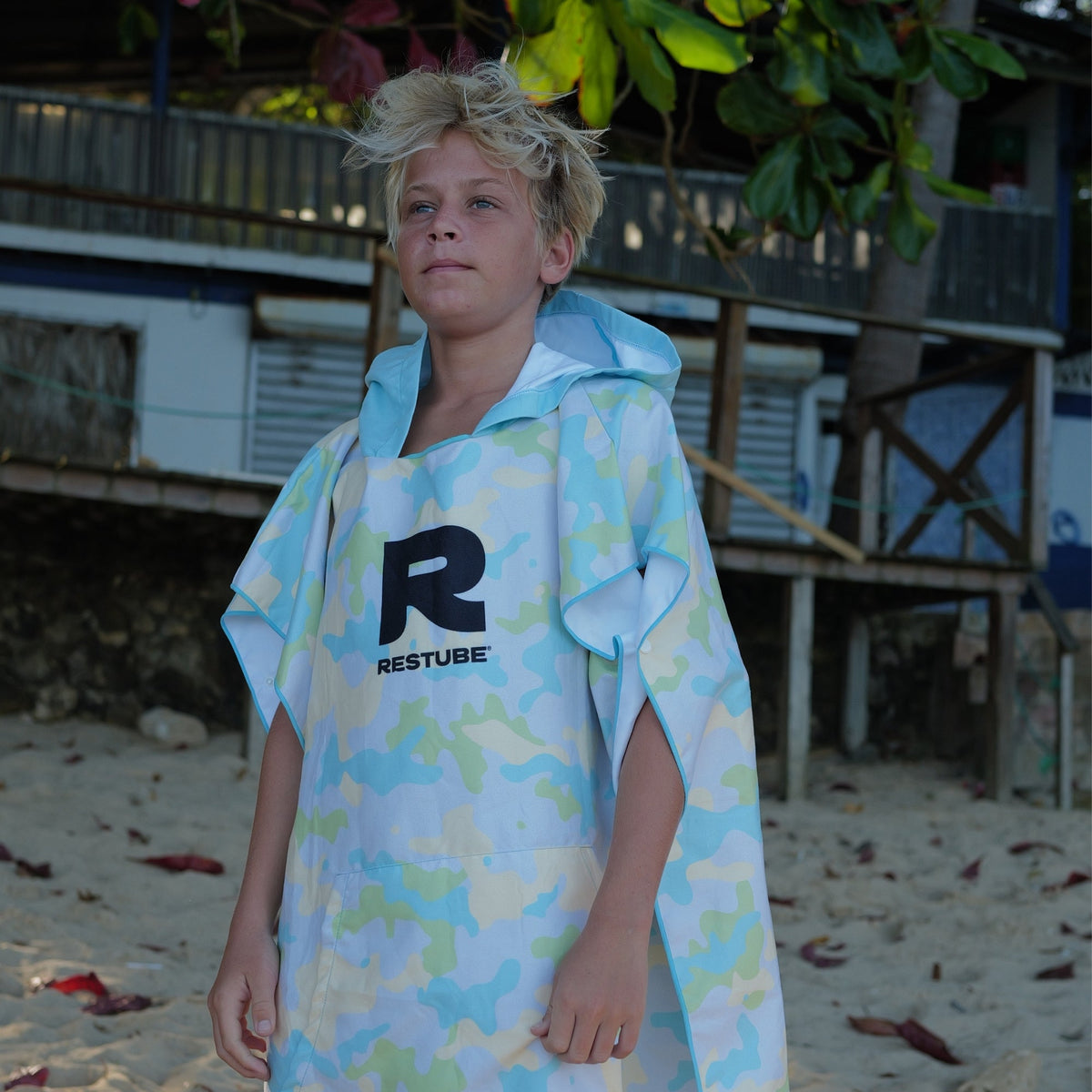 Boy wearing RESTUBE PONCHO KIDS light yellow camo at the beach - kids surf poncho with RESTUBE logo Philippines