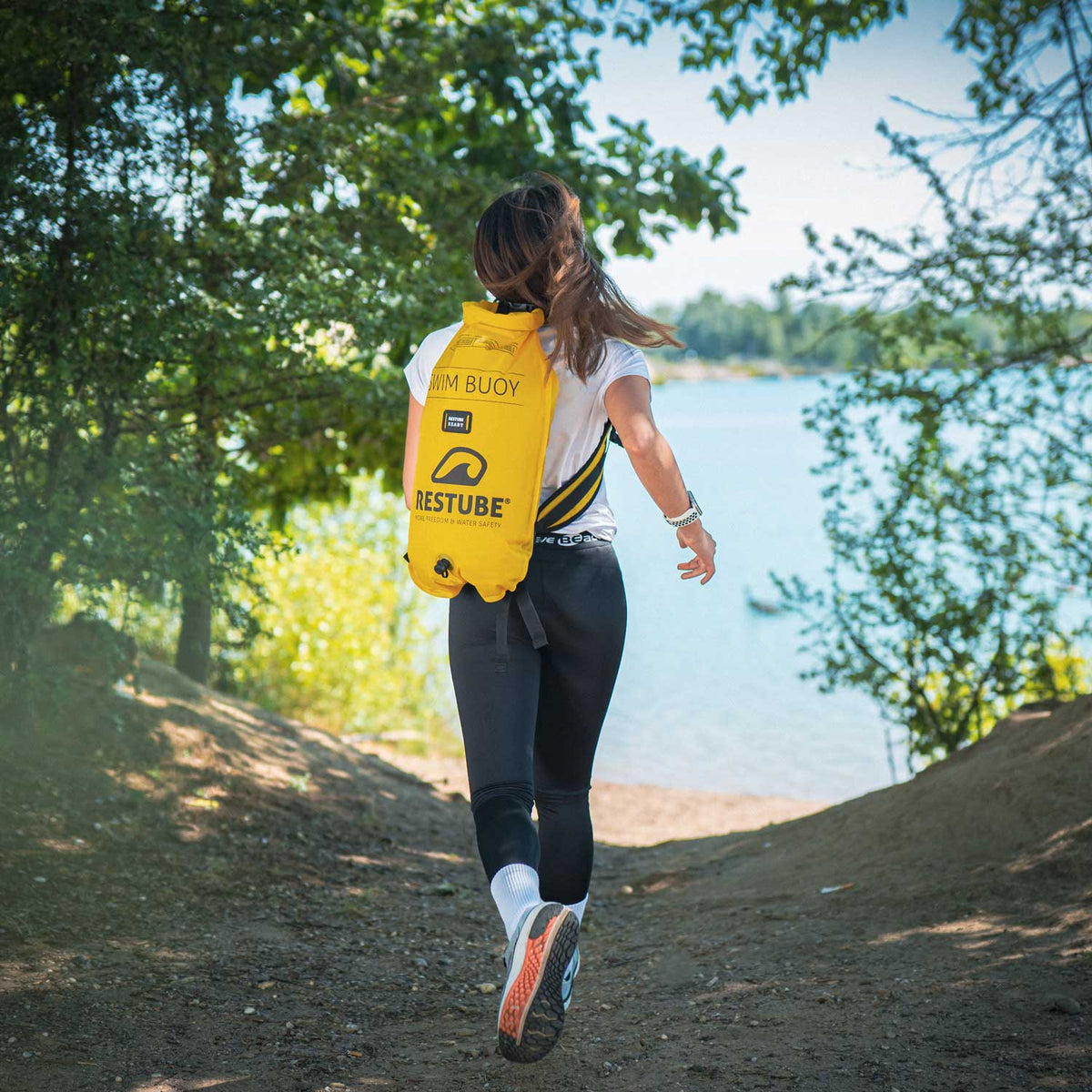 Woman running to lake with RESTUBE swim buoy as backpack using backpack straps Philippines