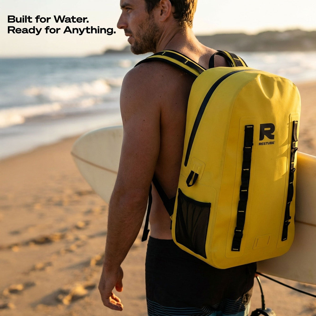 Man wearing yellow RESTUBE OCEAN 28L backpack on the beach holding a surfboard - outdoor water sports Philippines