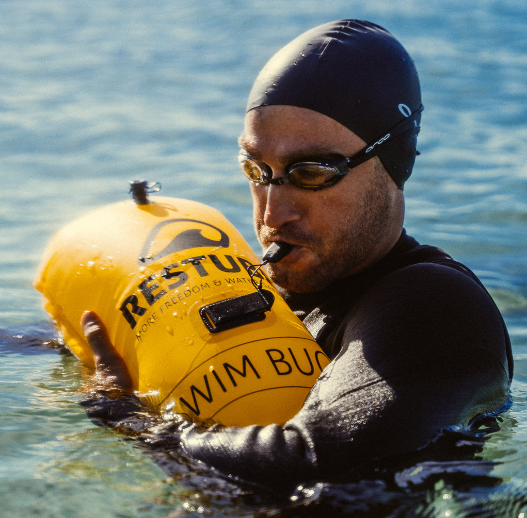 RESTUBE EMERGENCY WHISTLE hero image - swimmer blowing whistle with yellow safety buoy in water Philippines