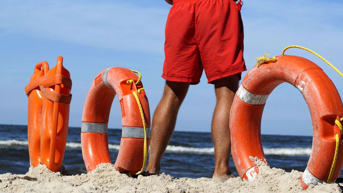 Lifeguard beside orange rescue buoys on a beach